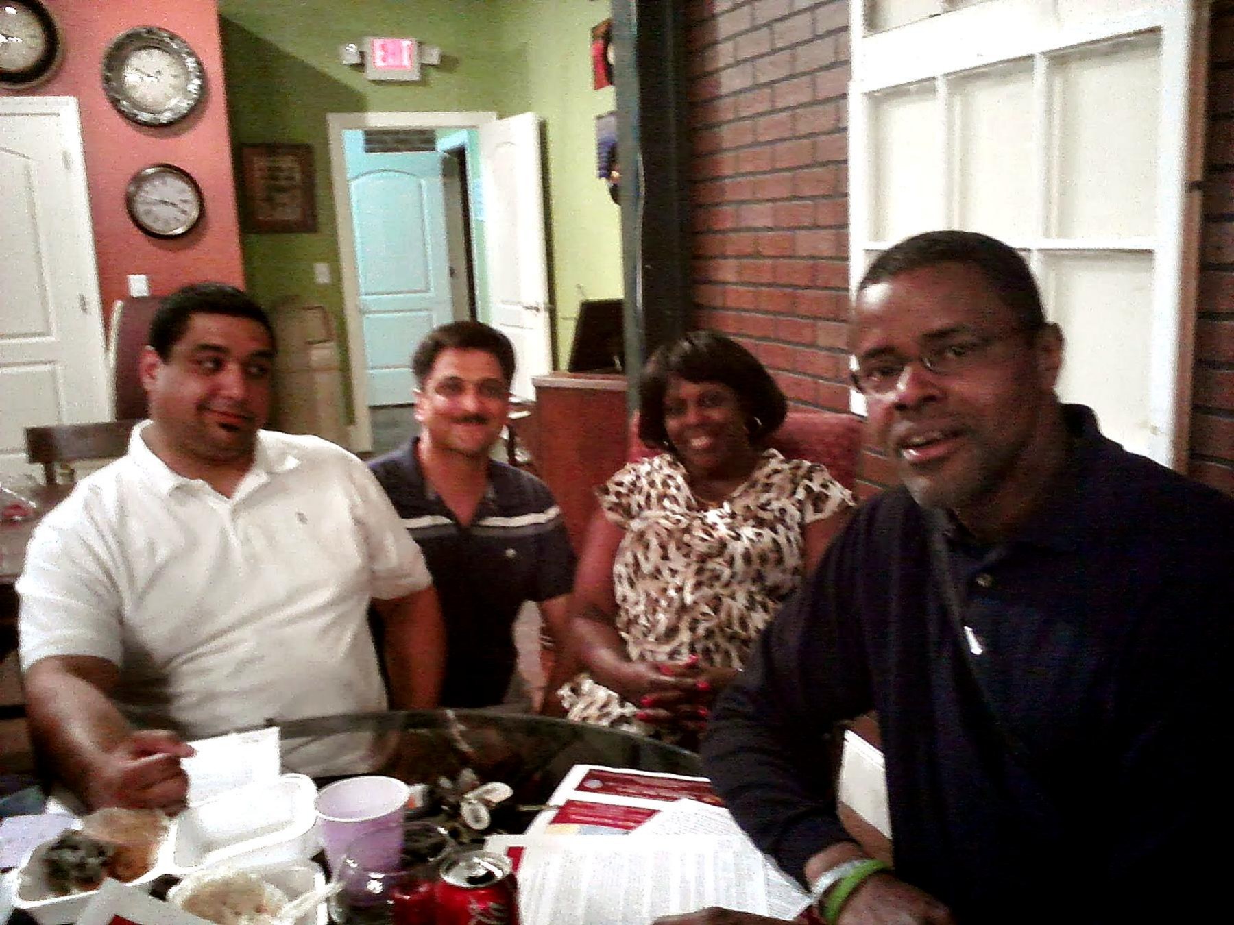 A group of community members talking together around a table indoors during a coalition gathering.
