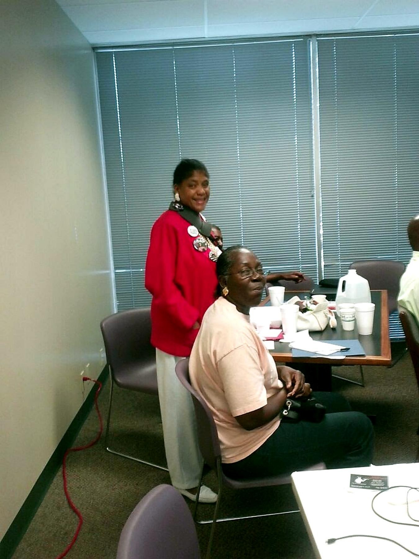 Two people talking one on one across a table in a small office during a healthcare outreach visit.