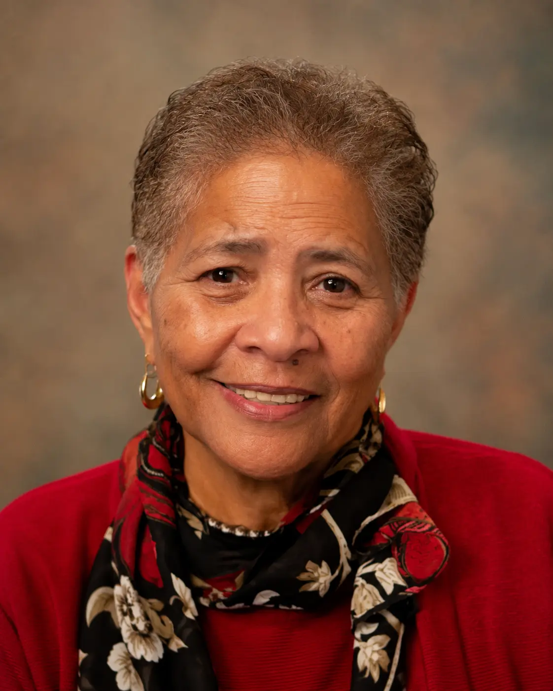 Portrait of CHCC Secretary-Treasurer Atty Charlotte Brown wearing a red jacket and floral scarf.