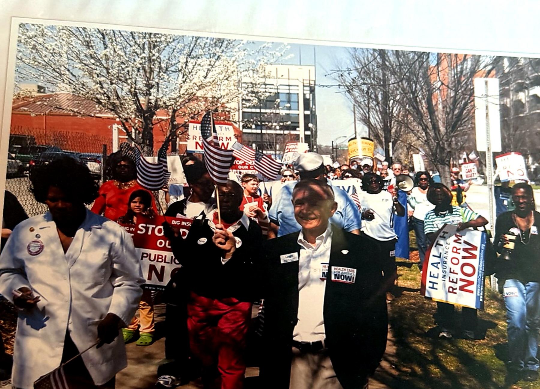 Marchers carrying American flags and healthcare reform signs along a Charlotte street.