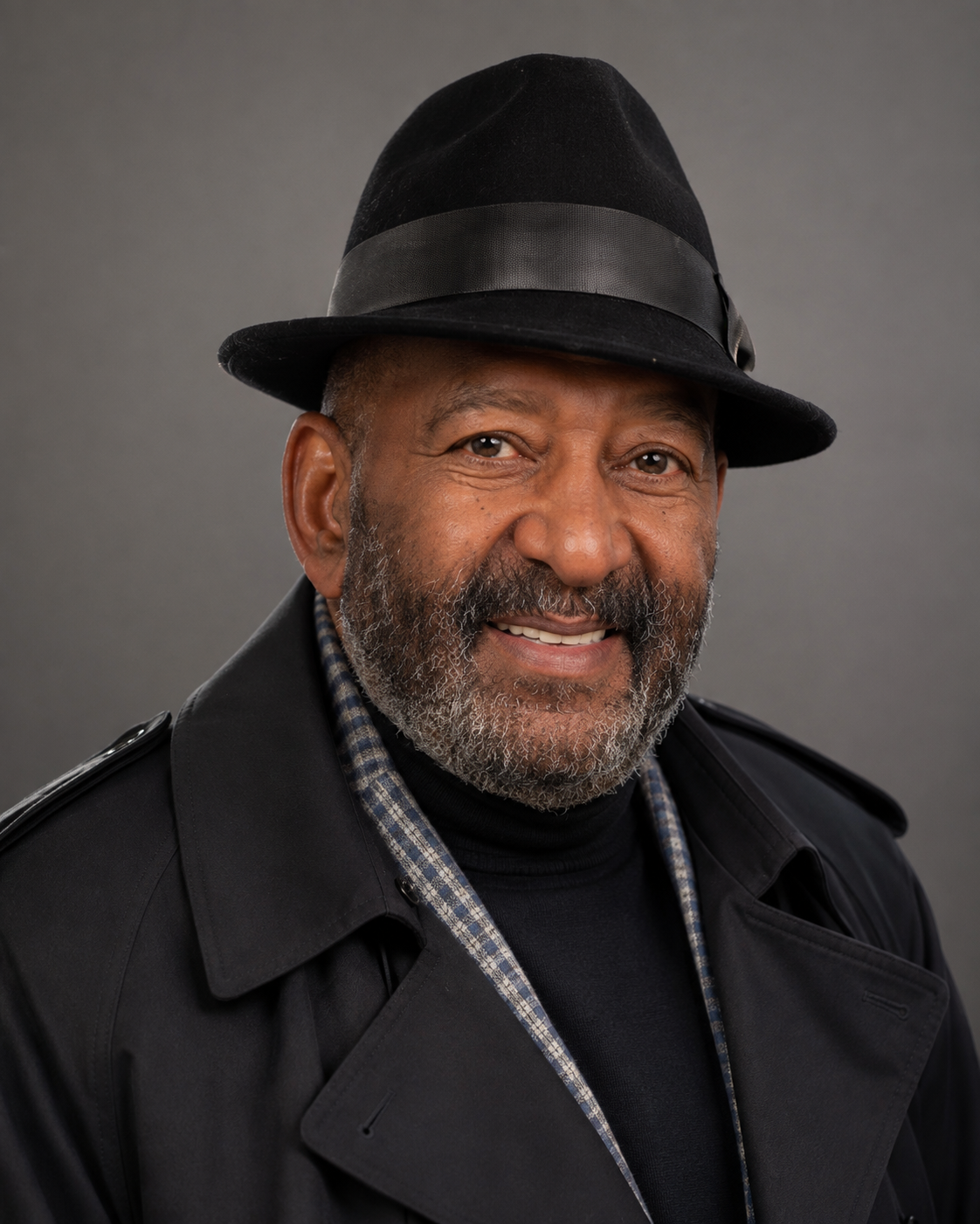 Portrait of CHCC Chair Mr. Lowell Faison wearing a black fedora and trench coat.
