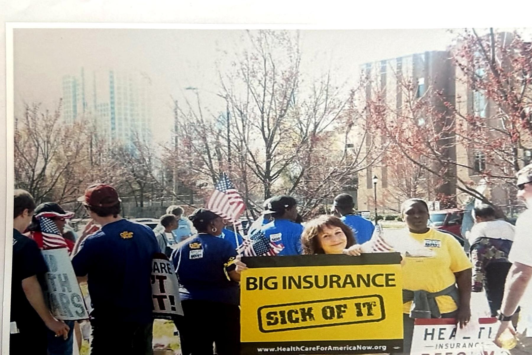 Demonstrators in a Charlotte street holding a yellow 'Big Insurance: Sick of It' sign during a healthcare rally.